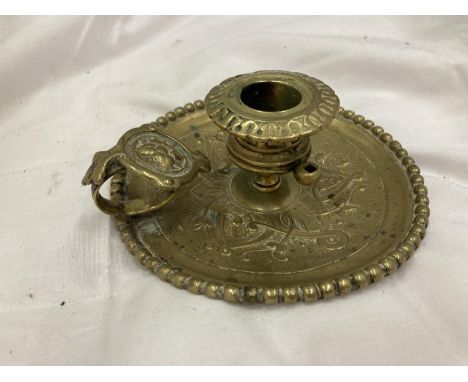 A BRASS EMBOSSED CANDLESTICK WITH HANDLE 