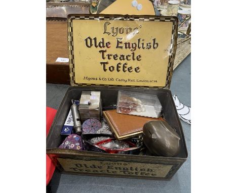 A VINTAGE LYONS' TREACLE TOFFEE TIN CONTAINING A QUANTITY OF COLLECTABLE ITEMS TO INCLUDE AN ACME WHISTLE, BRASS INKWELL, CIG
