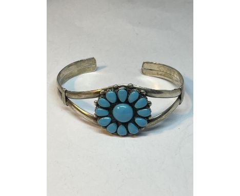 A MARKED SILVER BANGLE WITH TURQUOISE STONES IN A FLOWER DESIGN 