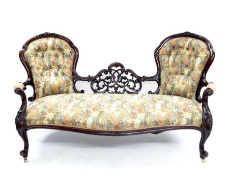 Victorian mahogany double spoon back sofa, the two stuffover button-back panels flanking a carved scrolled foliate centre sec