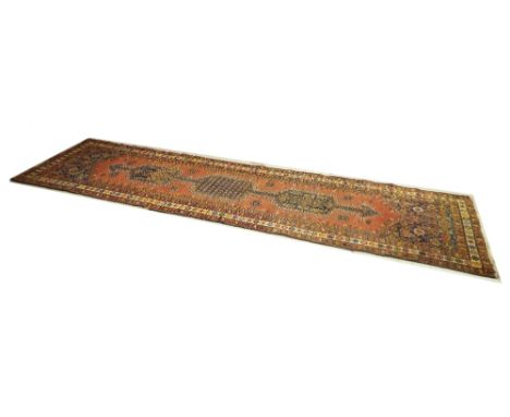 Persian runner, centrally decorated with a long blue medallion upon a burnt orange ground, 157" x 40"