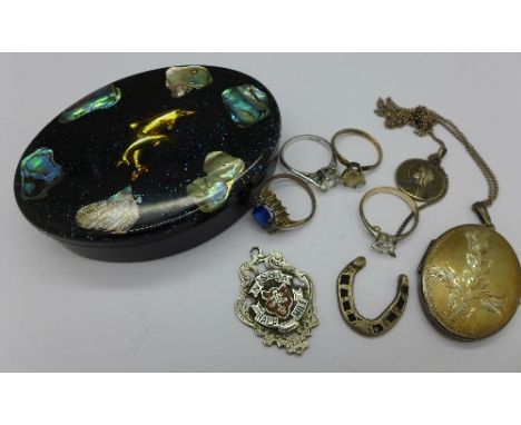 A silver locket, a silver and enamel fob, NSSA Half Mile, four rings and two silver charms in a box set with paua shell