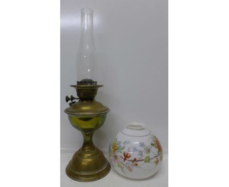 A brass oil lamp with chimney and a glass table lamp shade