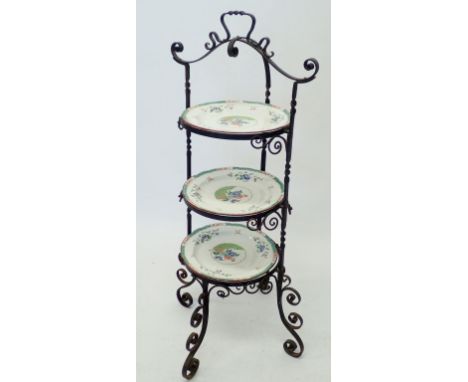 A wrought iron three tier cake stand with three inset Copeland Spode plates, 89cm high