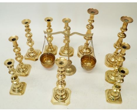 Five pairs of large brass candlesticks, largest 35cm tall and a set of balance scales
