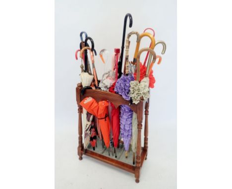 A collection of vintage umbrellas and parasols in turned wood stick stand 
