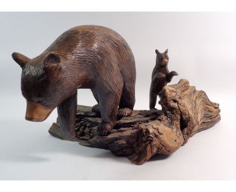 A Black Forrest style carved group of bear and cub mounted on a rustic trunk, signed to base, height 22cm