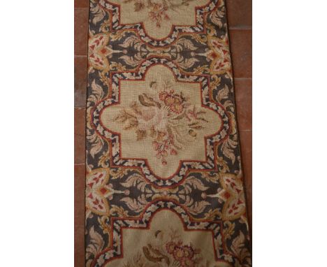 A needlepoint runner with repeating floral spray medallions on a foliate ground. L.420 W.57cm 