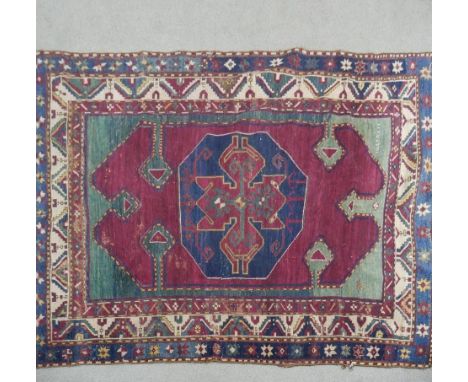 A Kazak rug with central lozenge medallion on burgundy field within jade spandrels (one signed) and foliate multiple borders.