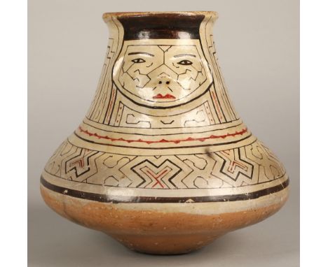 Shipibo terracotta pottery vessel, 20th C, squat base with a wide neck, geometric patterns in brown and red surround a face w