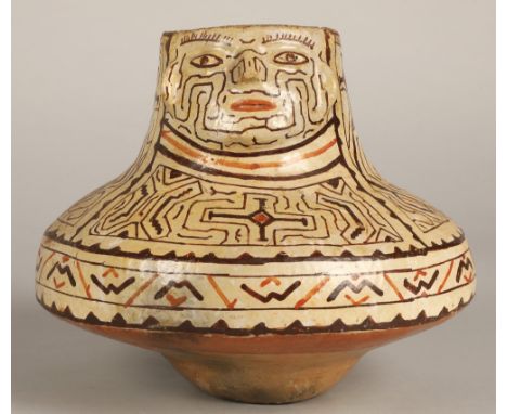 Shipibo terracotta pottery vessel, 20th C, geometric patterns in brown and red surround a face with protruding features. 19cm