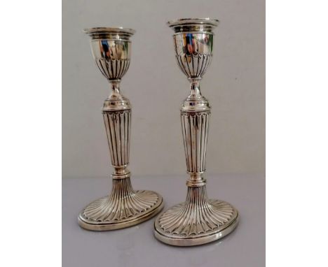A pair of Victorian silver candlesticks with fluted decoration on oval spreading bases by Henry Wilkinson &amp; Co., London, 