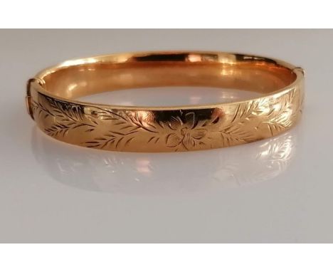 A 9ct yellow gold bangle with etched decoration, 62mm x 58mm, hallmarked for Birmingham, 1970, clasp good