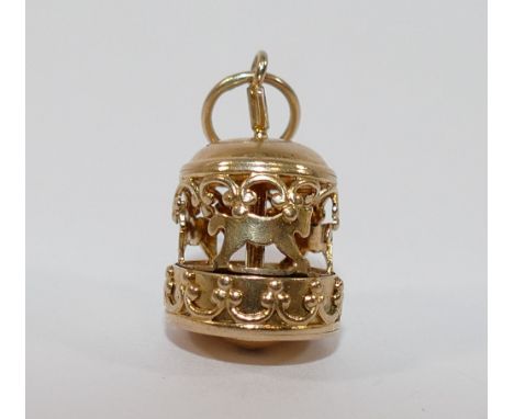 A yellow metal four-section puzzle ring, finger size V1/2, a yellow metal merry-go-round charm and a small yellow metal sunbu
