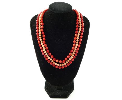 Two strings of individually knotted red coral bead necklaces, with a pair of matching drop earrings and a similar pink coral 