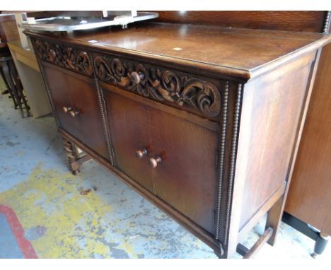 A vintage oak railback sideboard with decorative carving to two drawers above a two cupboard base & on raised barley-twist le