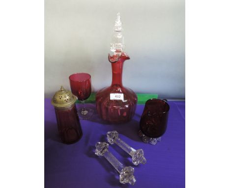 A cranberry glass decanter with clear glass stopper, a cranberry wine glass, jug, sifter and a pair of clear glass knife rest