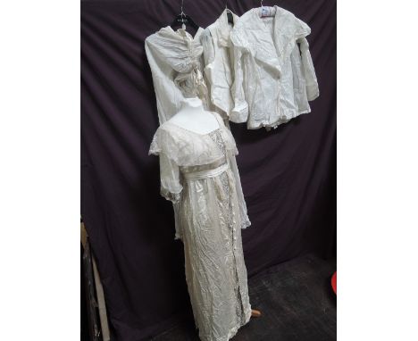 An Edwardian style cream silk dress having beaded panel and lace shawl collar, two ivory coloured cotton blouses, a cream cot