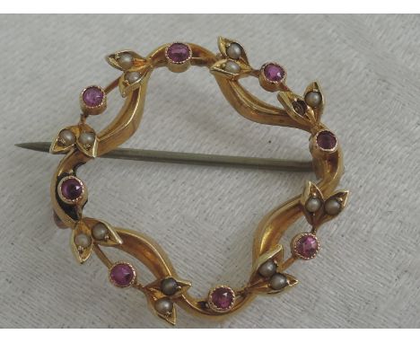A yellow metal brooch stamped 15ct of circular form having ruby and seed pearl decoration