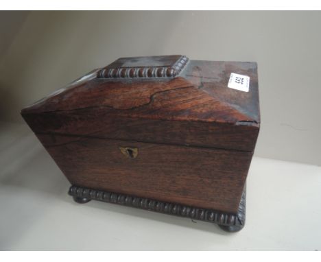 An early 19th century rosewood tea caddy of sarcophagus shape, on bun feet