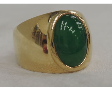 A yellow metal shaped band ring stamped 18K having an oval jade stone,  approx 3ct stone 