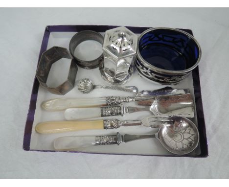 A selection of HM silver including a pepperette, two napkin rings, salt with blue glass liner, mother of pearl handled knife,