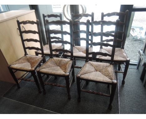 A set of six 20th century oak vernacular dining/kitchen chairs having wave ladder backs with rush seats and turned legs