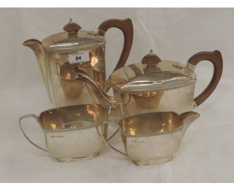 A four piece silver tea set of plain boat form having fruit wood handles, gadrooned rims and scallop shell decoration to arch