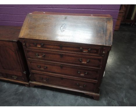 An early 19th century oak bureau having shell inlay decoration, with fall flap and drawer interior, over drawers and bracket 