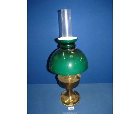 A brass based oil lamp having glass chimney and green domed shade.