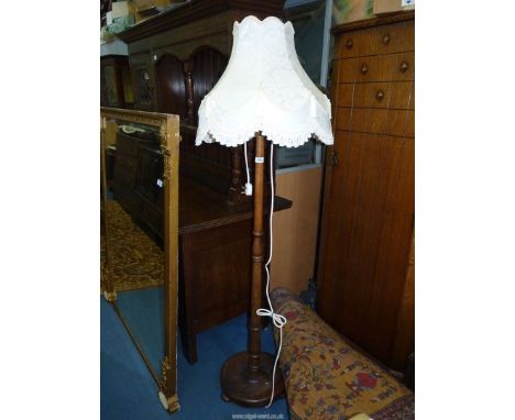A darkwood standard lamp having an octagonal cream shade with tasselled details.