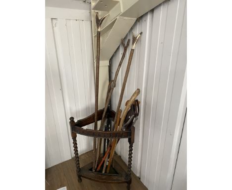 A stick stand with walking sticks, some horn handled, a shooting stick and an unusual black leather swagger stick