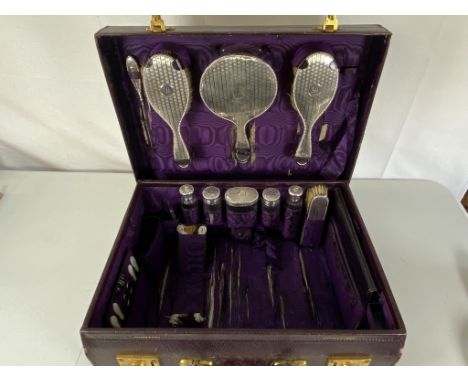 A silver vanity set in leather case comprising hair brushes, clothes brush, mirror, button hook &amp; 5 bottles/jars.&nbsp; H