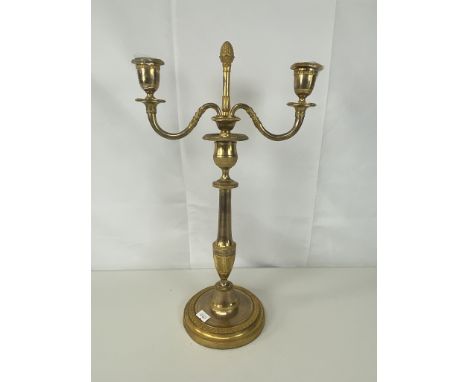 An early 19th century Swedish neo-classical gilt brass two-branch candelabra with feather gadrooned border and baluster stem,