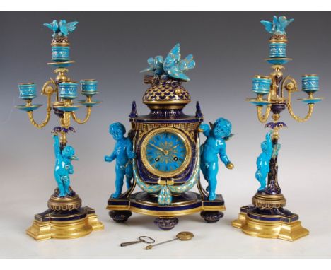 A late 19th century French porcelain turquoise and cobalt blue ground clock garniture, comprising; a mantle clock with circul