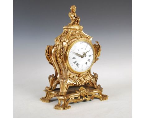 A 19th century French Rococo style ormolu mantle clock, the circular convex enamel dial with Arabic and Roman numerals, the t