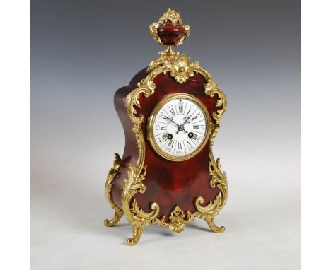 A late 19th century gilt metal mounted mantle clock, the circular porcelain dial with Arabic and Roman numerals, the twin tra