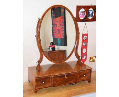 A large 19th century mahogany and boxwood strung dressing table mirror, the hinged oval mirror plate on a breakfront base fit