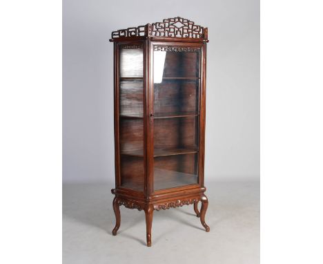 A Chinese dark wood display cabinet, early 20th century, with pierced surmount above a glazed cupboard door, opening to a fit