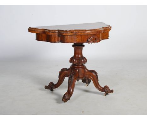 A Victorian walnut demi-lune card table, the shaped hinged top above a plain frieze centred with scroll and foliate carved de