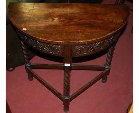 An early 20th century barley twist oak demi-lune side table, having low relief carved frieze