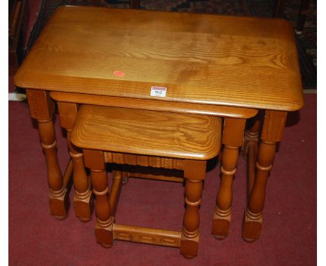 An Ercol mid elm nest of three occasional tables, together with a matching circular low occasional table (2)