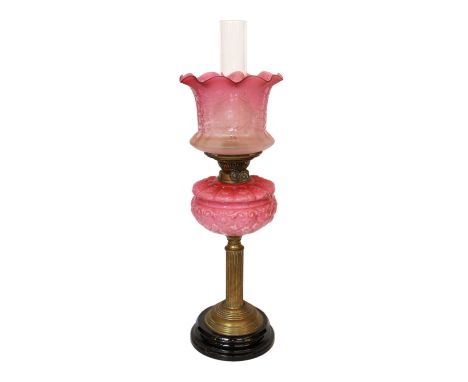 A late Victorian brass oil lamp with opaque pink glass reservoir, duplex mechanism, cranberry tinted etched glass shade and f