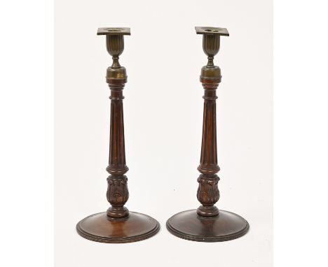 A pair of mahogany candlesticks, early 20th c, with brass sconces and nozzles, 32cm h A piece of the base of one candlestick 