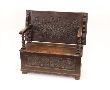 An oak monks bench/table, carved decoration to the flap-over top, box seat, foliate carved decoration to the front panel, ope