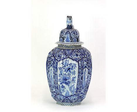 A Dutch Delft blue and white covered vase, probably 19th Century, lightly fluted shouldered form, panelled decoration of flow