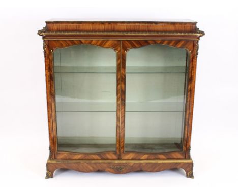 A Napoleon III walnut vitrine, with gilt metal mounts, two glazed doors enclosing plate glass shelves, rounded corners, brack