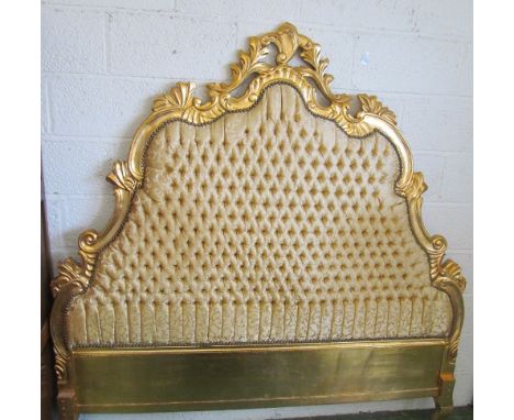 A large gilt and button upholstered headboard