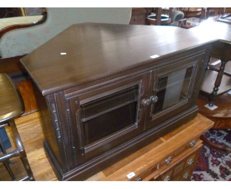 An Ercol dark elm finished corner fitting low TV stand / cabinet with two glazed panelled doors, on plinth base.