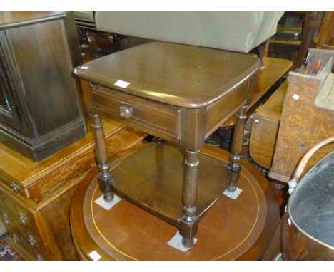 An Ercol dark elm finished bedside table / lamp table, with single frieze drawer above open recess. 